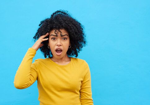 Shot of a woman looking astonished while posing against a blue background