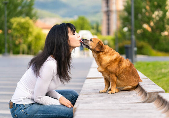 A woman kissing with her old dog in the park