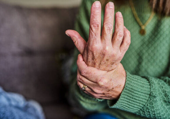 Hands of a senior woman clutching at her sore wrist.