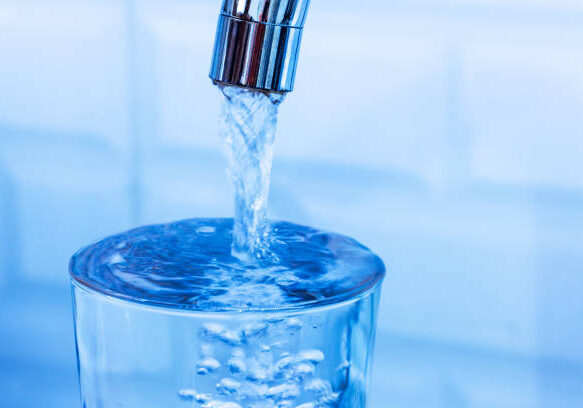 Pouring glass of fresh water from tap in kitchen