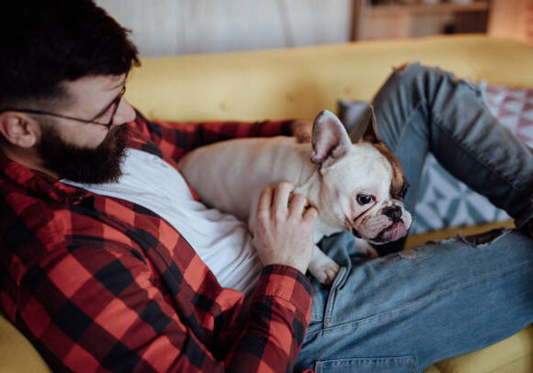 Man relaxing in sofa and cuddling with his dog